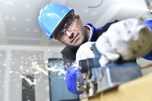 Closeup of carpenter cutting wood with electric saw