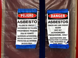 8333590 - bilingual asbestos warning signs on plastic covering a front door