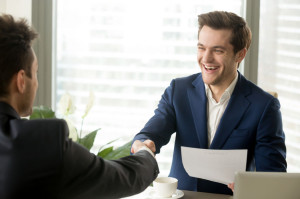 Happy excited business partners handshaking after signing mutual