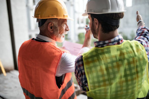 Engineer, foreman and worker discussing in building construction site